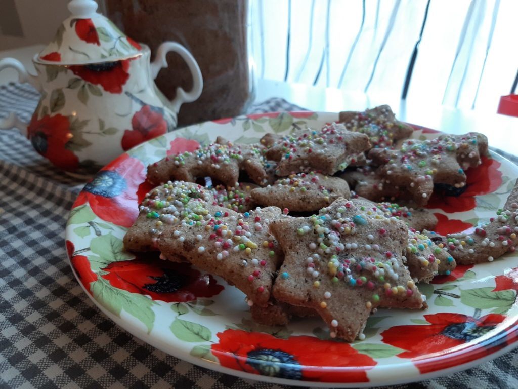 Biscotti befanini: dalla Versilia per tradizione biscotti su piatto con fiori rossi sullo sfondo zuccheriera con fiori rossi