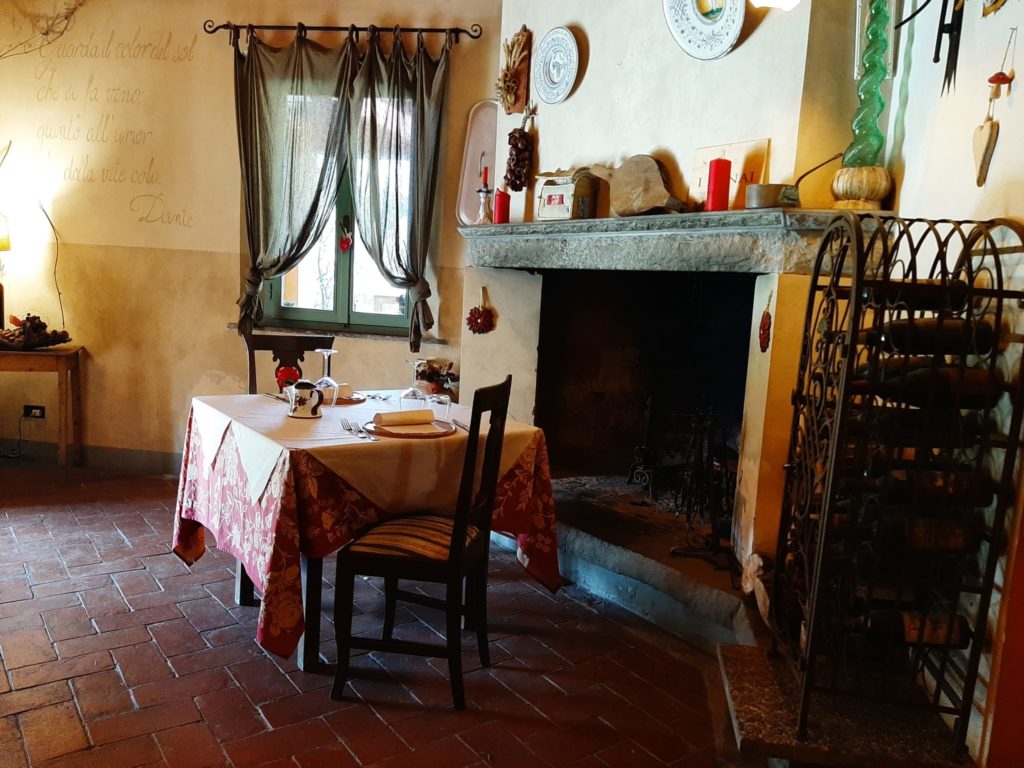 Dove mangiare in Toscana fuori dalla “pazza folla” - interno del ristorante il convio camino e tavolo per due 